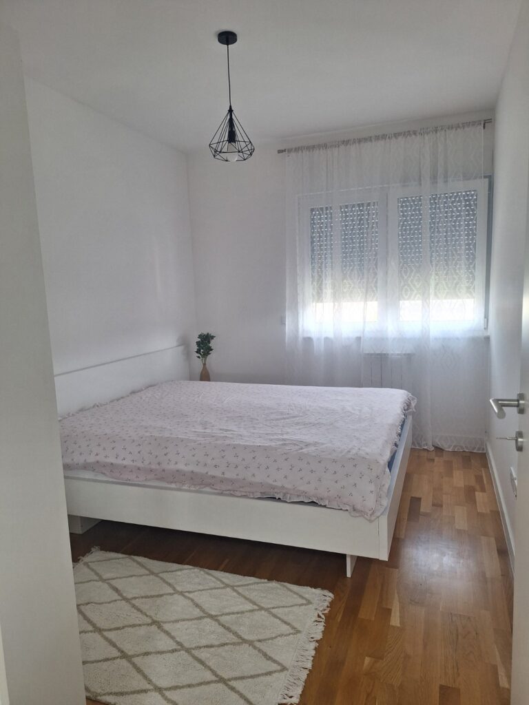 Svijetla spavaća soba apartmana Tuzla Tower Apt sa bračnim krevetom i velikim prozorom