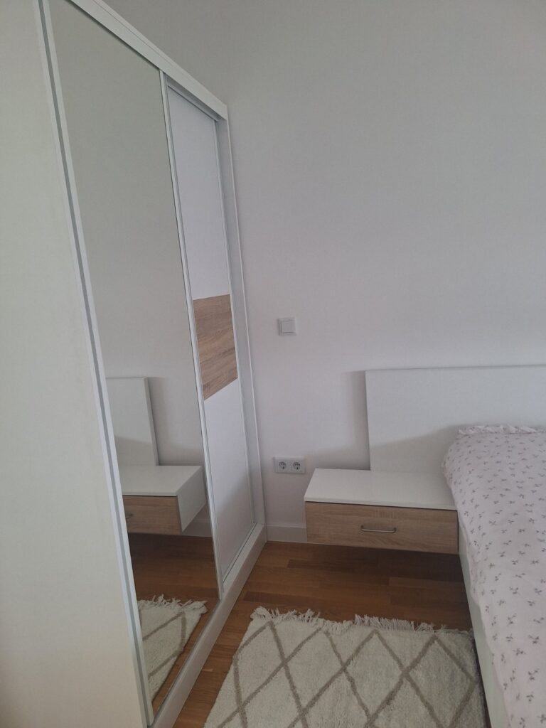 Spavaća soba apartmana Tuzla Tower Apt sa garderoberom, ogledalom i bračnim krevetom