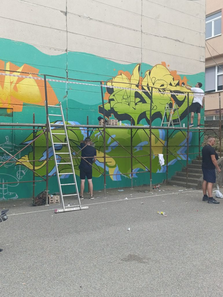 Umjetnici oslikavaju veliki mural na zidu tokom uličnog umjetničkog događaja u Tuzli